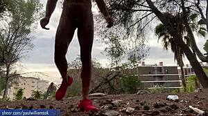 Svalnatý muž ukazuje svou kondici tím, že si užívá nahé dřepy v přírodě